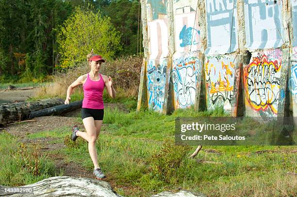 caucasian woman running near abandoned building - pete vandal stock-fotos und bilder