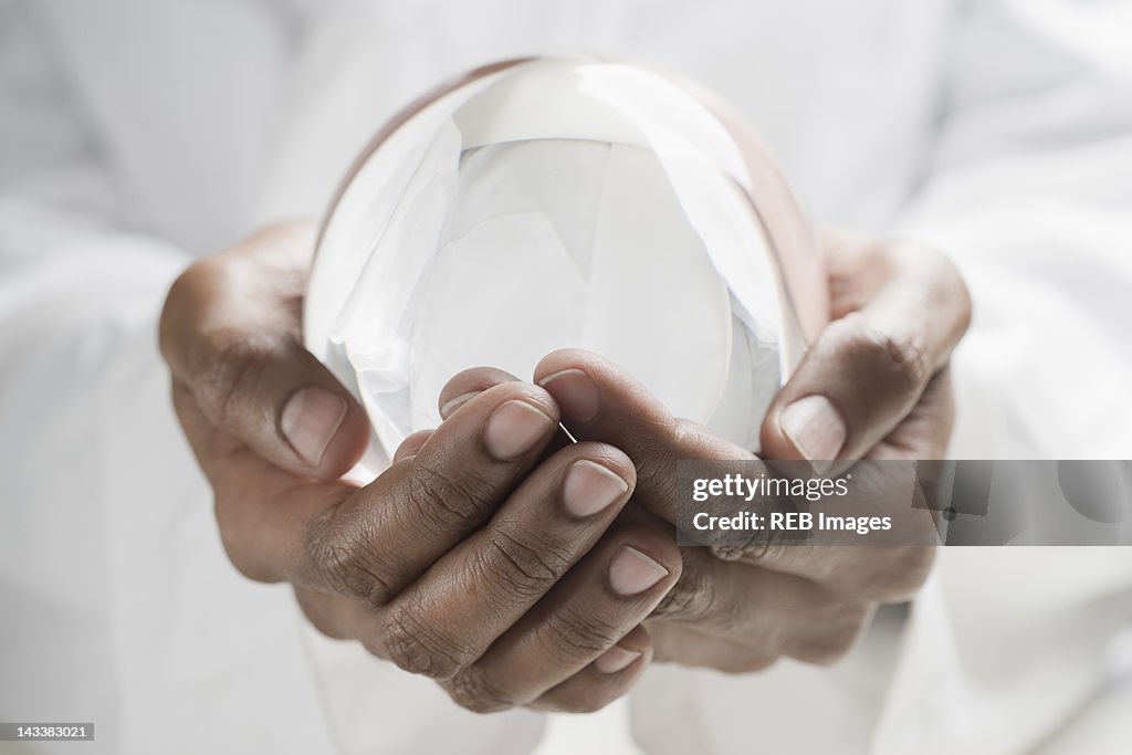 Close up of mixed race man holding crystal ball