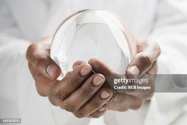 close up of mixed race man holding crystal ball - fortune telling stock pictures, royalty-free photos & images