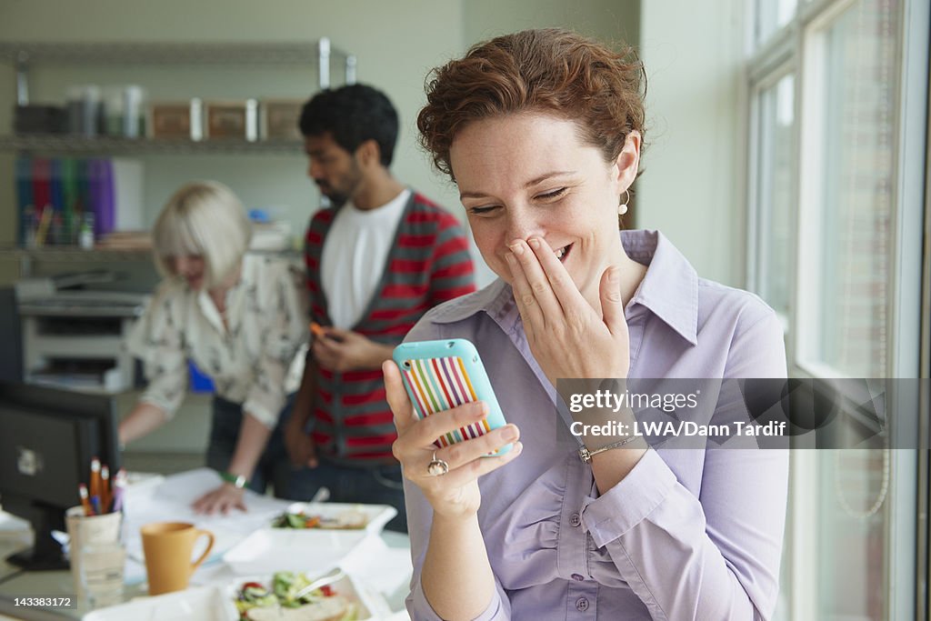 Businesswoman laughing at text message