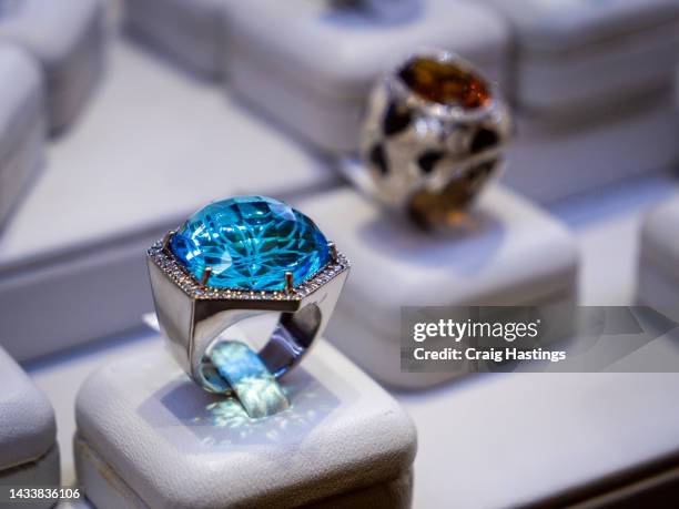 macro close up sapphire & topaz coloured gemstone set rings arranged in a row in jewellery store shop setting. luxury ring display with shining colourful stones and diamonds. high end luxury shopping. - topaz fotografías e imágenes de stock
