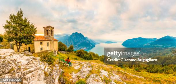 woman admiring from a bench the enchanting view of iseo lake, san defendente mount, lovere, brescia province, lombardy, italy - bergamo stock pictures, royalty-free photos & images