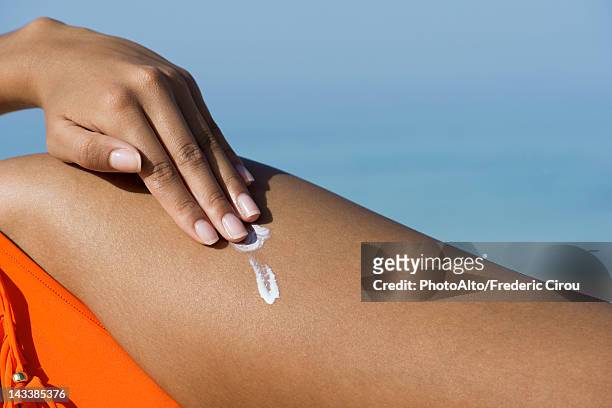 woman applying suncreen at the beach, cropped - bräune stock-fotos und bilder