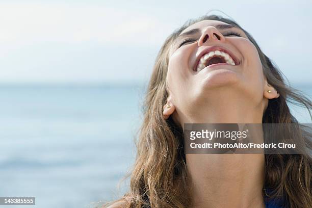 young woman laughing outdoors with head back and eyes closed - head back stock pictures, royalty-free photos & images