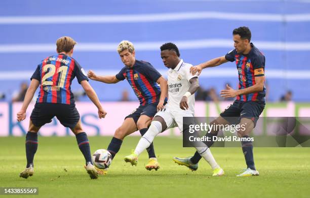 Vinicius Junior of Real Madrid is challenged by Frenkie de Jong, Sergi Roberto and Sergio Busquets of FC Barcelona during the LaLiga Santander match...