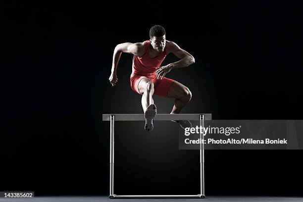 male athlete clearing hurdle - hurdling photos et images de collection