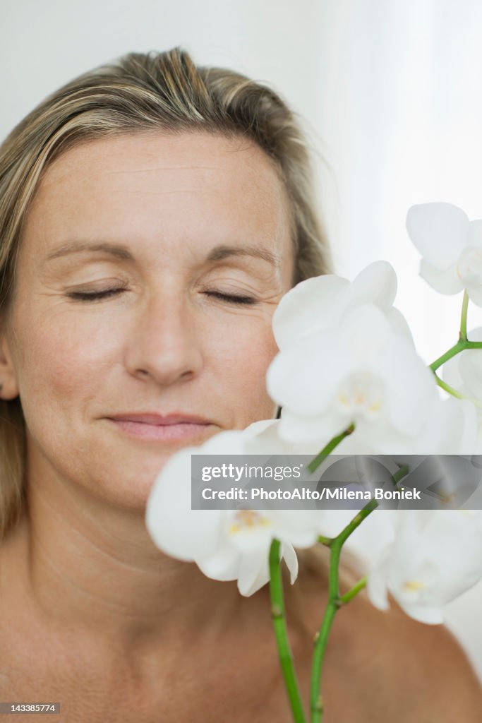 Woman smelling flowers, eyes closed