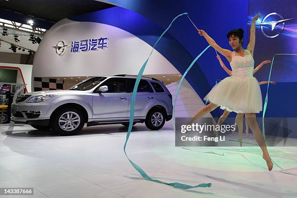 Dancers perform beside a Haima 7 Vehicle during the 2012 Beijing International Automotive Exhibition at China International Exhibition Center on...