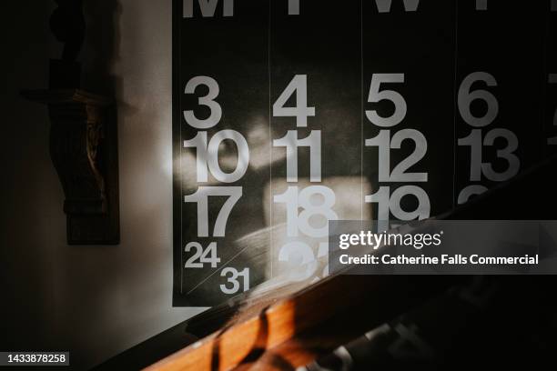 close-up of sun beams illuminating a large wall calendar - kalender stockfoto's en -beelden