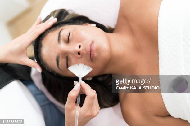 young woman doing a facial cleaning in the saloon. beautician doing facial cleaning to patient. concept of care and facial treatment. - esthetician stock pictures, royalty-free photos & images