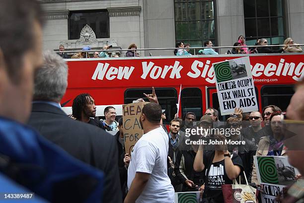 Tourist bus passes by as protesters chant near Wall Street during an ACT-UP and Occupy Wall Street demonstration on April 25, 2012 in New York City....