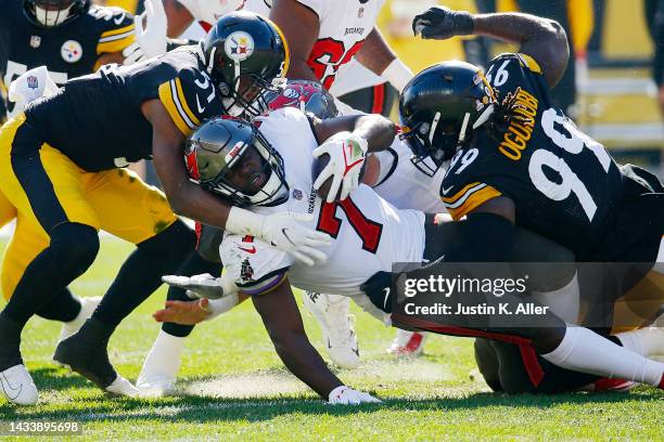 Leonard Fournette of the Tampa Bay Buccaneers is tackled by Myles Jack and Larry Ogunjobi of the Pittsburgh Steelers during the first half at...