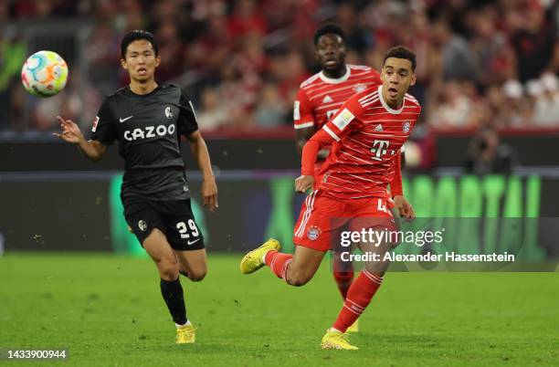 Jamal Musiala of Bayern Munich breaks away from Jeong Woo-Yeong of SC Freiburg during the Bundesliga match between FC Bayern München and Sport-Club...