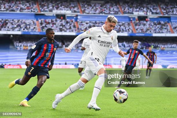 Federico Valverde of Real Madrid CF runs with the ball Ousmane Dembele of FC Barcelona during the LaLiga Santander match between Real Madrid CF and...