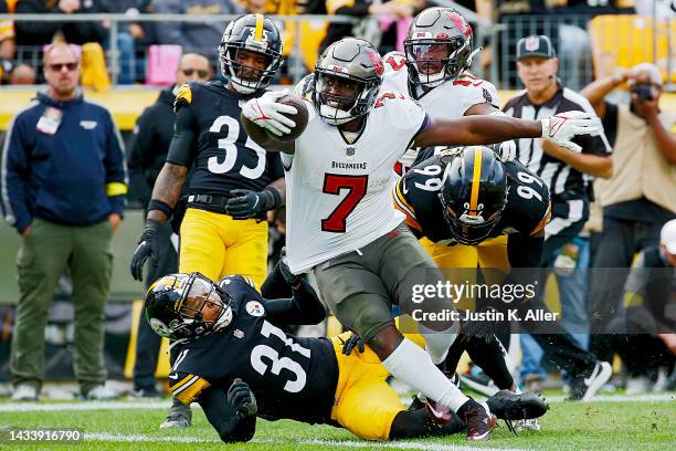 Leonard Fournette of the Tampa Bay Buccaneers runs the ball against Mark Gilbert of the Pittsburgh Steelers during the fourth quarter at Acrisure...