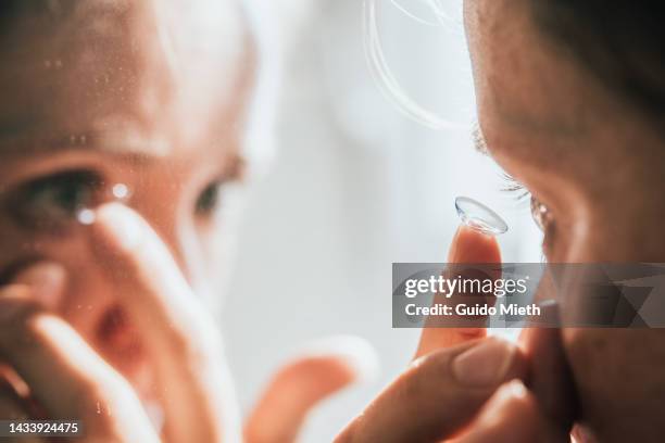 woman putting in contact lens. - lens eye stock-fotos und bilder