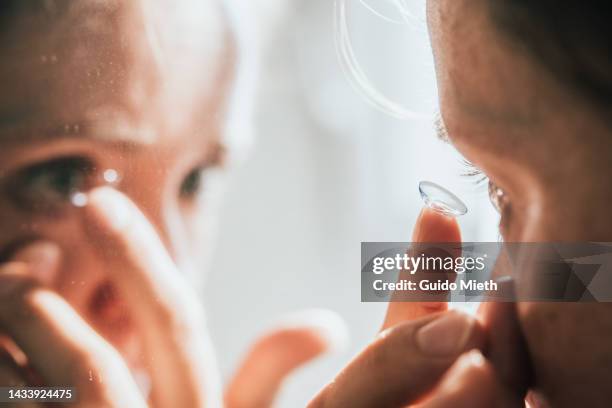 woman putting in contact lens. - portrait lens flare stock pictures, royalty-free photos & images