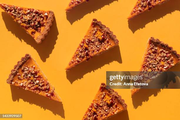 several pieces of pumpkin cake with walnuts on orange table. a traditional autumn dish for thanksgiving day and halloween. flat lay style - pie stockfoto's en -beelden