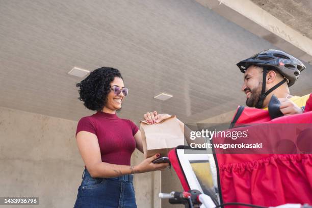 male courier with bicycle delivering take away food to the customer - gig economy stock pictures, royalty-free photos & images