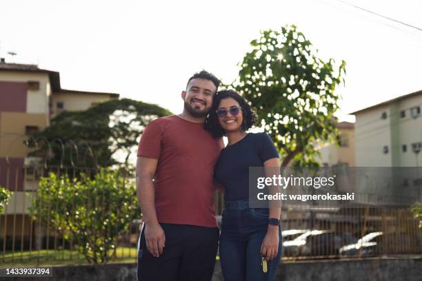 retrato de una joven pareja sonriente en un condominio residencial - viviendas asequibles fotografías e imágenes de stock