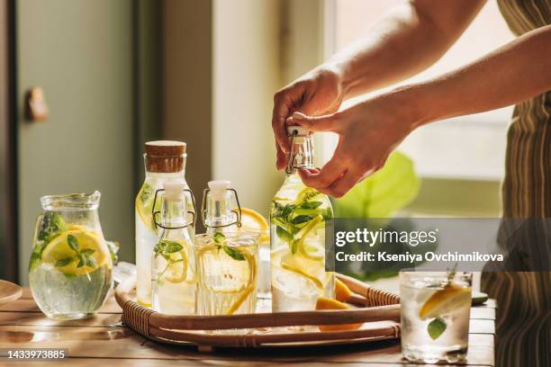 unrecognizable person pouring lemonade from jug into the glass - cocktail making fotografías e imágenes de stock