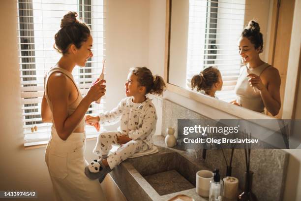 young mother brushing teeth with her little daughter. positive emotions and happiness - mouth hygiene brush stock pictures, royalty-free photos & images