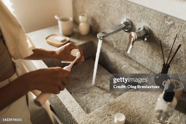 woman's hands smearing paste on electric toothbrush. personal hygiene - brushing stock pictures, royalty-free photos & images