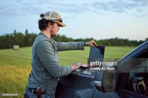 man using a laptop while working on a farm - landskap stockfoto's en -beelden