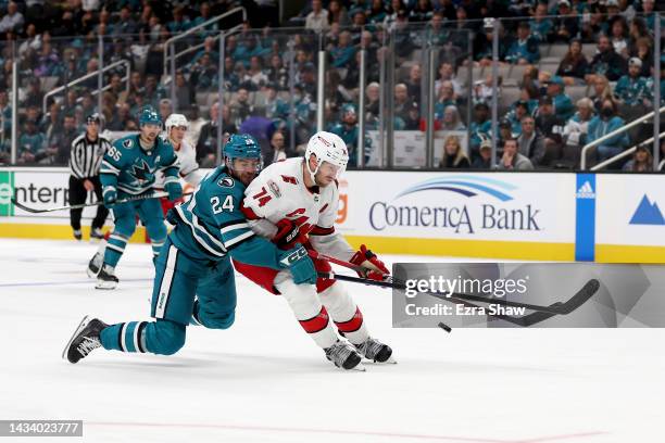 Jaycob Megna of the San Jose Sharks and Jaccob Slavin of the Carolina Hurricanes go for the puck in the third period at SAP Center on October 14,...