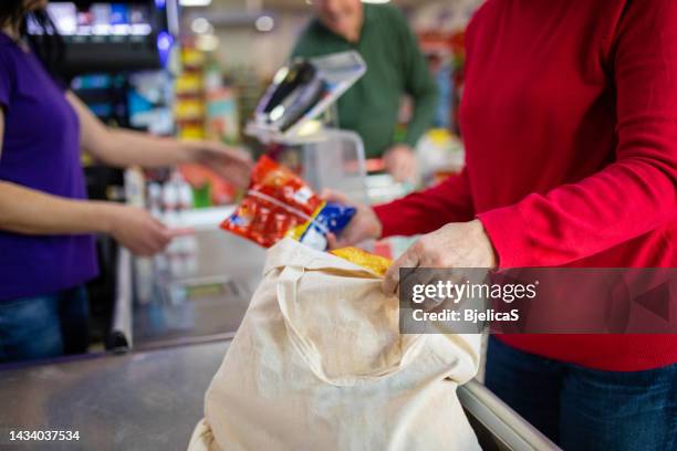 husband and wife packing groceries in reusable bag in supermarket - herbruikbare tas stockfoto's en -beelden