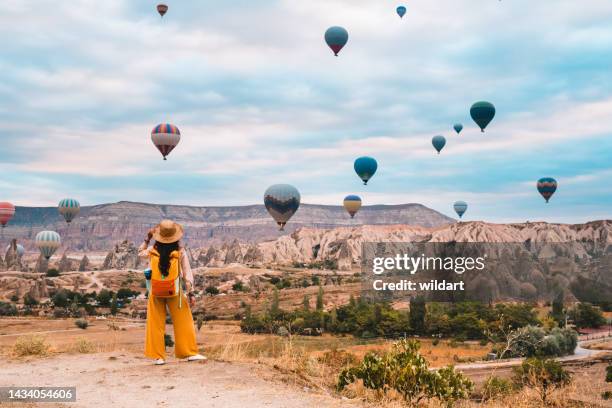 旅行者のバックパッカーの女の子は、ネブシェヒル、トルコのカッパドキアギョレメで熱気球と妖精の煙突を見ている - 海外旅行 ストックフォトと画像
