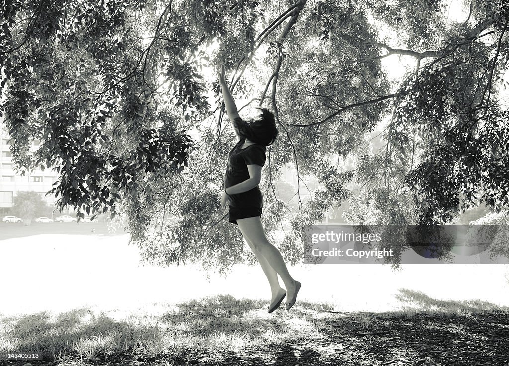 Woman jumping to touch tree