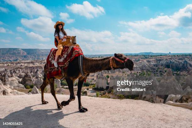 traveler backpacker mädchen reitet auf einem kamel in love valley in kappadokien in nevsehir, türkei - hot air balloon ride stock-fotos und bilder