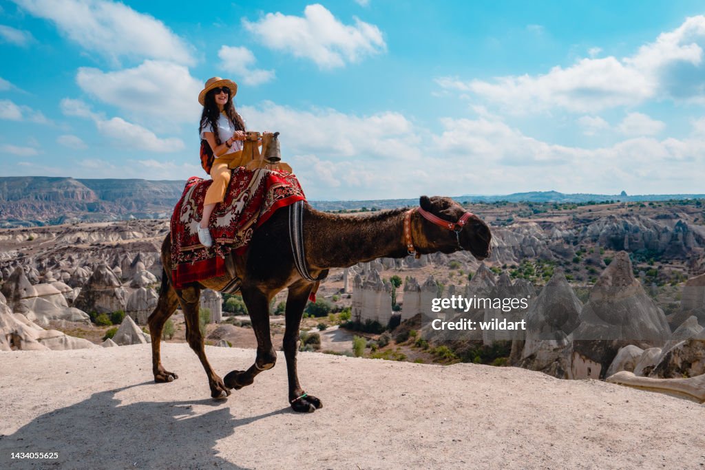 Traveler backpacker girl is riding a camel in Love Valley at Cappadocia in Nevsehir , Turkey