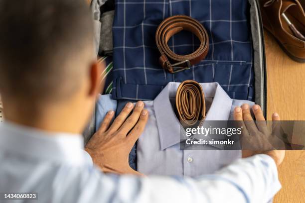 hombre empacando ropa - leather belt fotografías e imágenes de stock