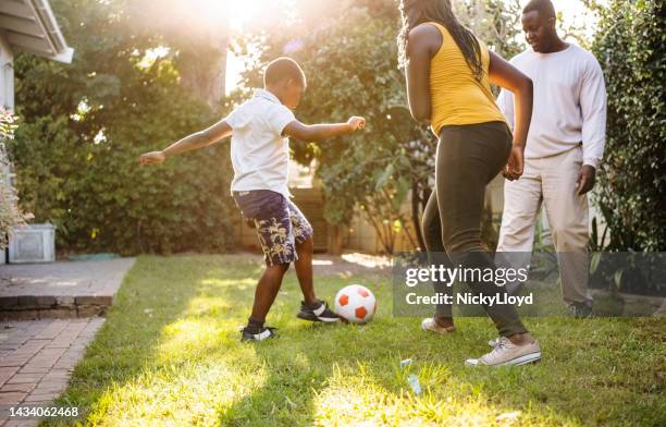 african family playing soccer in their backyard - vrijetijd sport en spel stockfoto's en -beelden