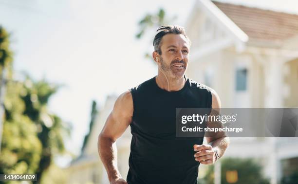 runner, fitness and senior man running, listening to music outdoor in neighborhood for workout wellness, energy and healthy lifestyle motivation. sports person with exercise training goal in street - sports training bildbanksfoton och bilder