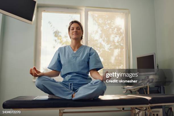 female nurse exercising yoga at doctor's office. - nurse meditating stock pictures, royalty-free photos & images