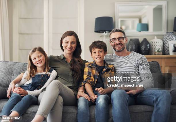family, portrait smile and relax on living room sofa in happiness for bonding time together in the lounge at home. happy mother, father and children relaxing on a couch enjoying break at the house - vier personen stockfoto's en -beelden