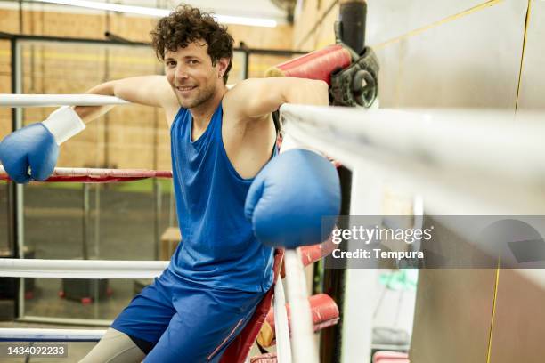 portrait of male boxer flashing a smile while resting in boxing ring corner after strenuous sparring session in gym - argentina training session stock pictures, royalty-free photos & images