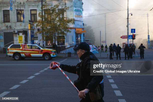 Police officer encloses the explosion site by red-and-white warning tape after attack from “kamikaze drones” on October 17, 2022 in Kyiv, Ukraine. In...