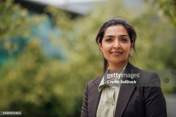 businesswoman looking into camera subtly smiling - girl power expressão inglesa imagens e fotografias de stock