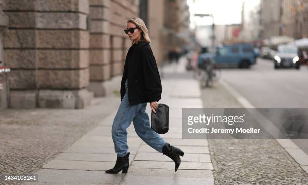 Lena Nussbaum is seen wearing black sunglasses from YES MY LOVE, black sweater, black jacket and black leather clutch bag from YES MY LOVE, blue...