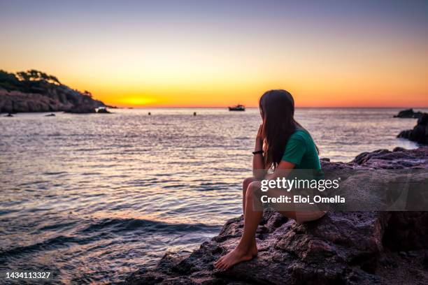 jeune femme heureuse contemplant le coucher de soleil pittoresque - calella de palafrugell photos et images de collection