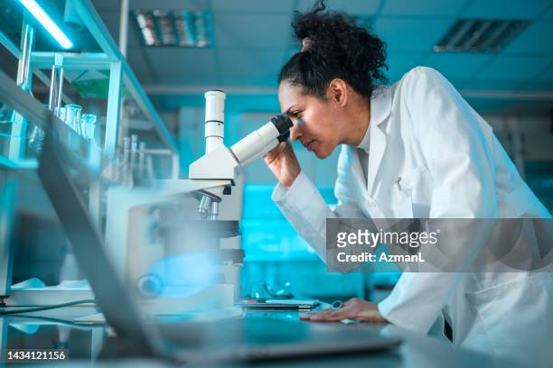 apothekerin schaut durch ein mikroskop - person mikroskop stock-fotos und bilder