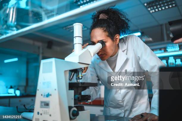 scientific research performed by a female chemist - medical research microscope stock pictures, royalty-free photos & images