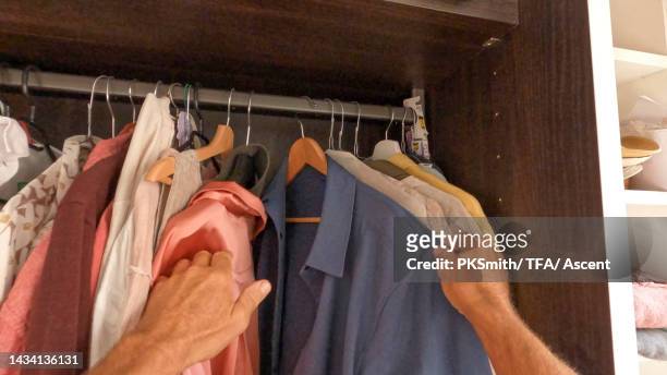 personal perspective of man choosing clothes from cupboard - kleidungsstück stock-fotos und bilder