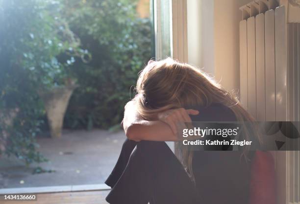 woman crouching with head on her knees - mourning stock pictures, royalty-free photos & images
