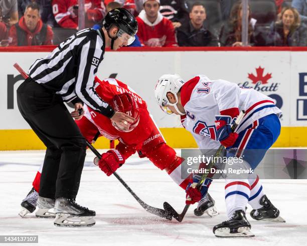 Linesman Kilian McNamara drops the puck between Dylan Larkin of the Detroit Red Wings and Nick Suzuki of the Montreal Canadiens during an NHL game at...