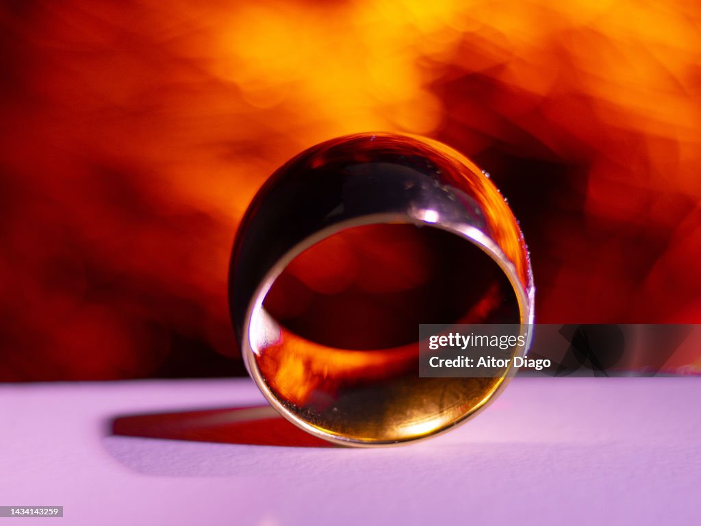 Close up of a gold wedding band. There is a fire in the background.